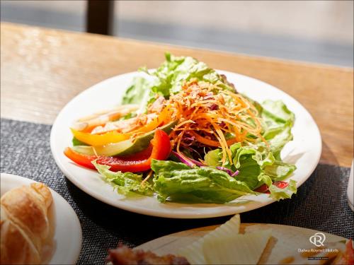 ein weißer Teller mit Salat auf dem Tisch in der Unterkunft Daiwa Roynet Hotel Sapporo-Susukino in Sapporo