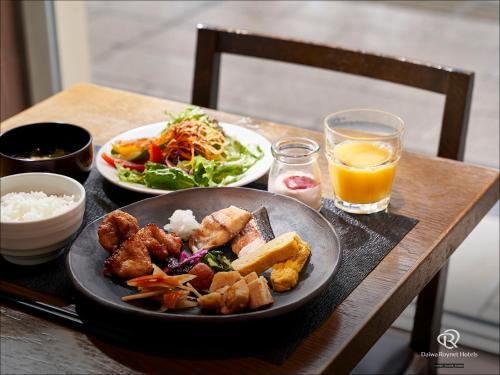 ein Tisch mit einem Teller Essen und einer Schüssel Reis in der Unterkunft Daiwa Roynet Hotel Sapporo-Susukino in Sapporo