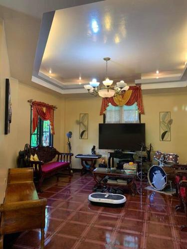 Una sala de estar con un televisor, un sofá y una mesa. en B2 Guest House A-Main, en Guiuan