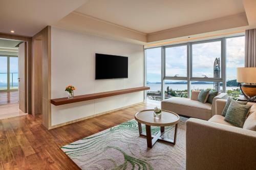 a living room with a couch and a tv at Shenzhen Dameisha Kingkey Palace Hotel in Shenzhen