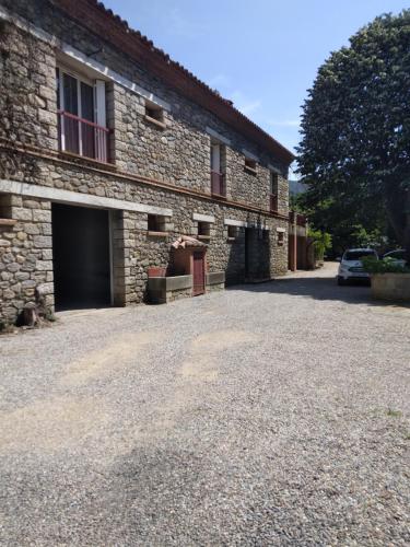 a stone building with a car parked in front of it at El Paller Mas Vidalou in Céret