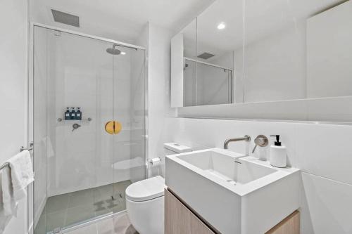 a white bathroom with a sink and a shower at One bedroom apartment in the heart of CBD in Adelaide