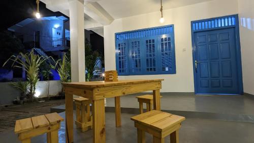 a wooden table and benches in a room with blue doors at Hiriketiya Hideaway in Dickwella