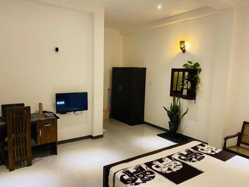 a room with a bed and a desk and a television at Ceylon Avenue in Habaraduwa