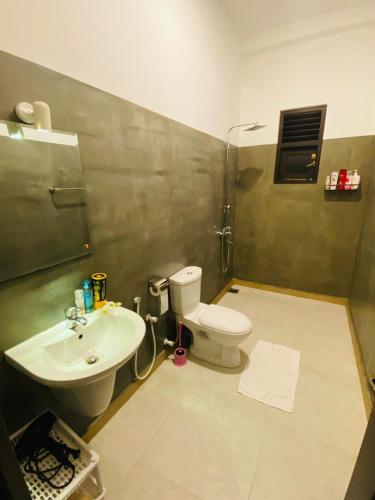 a bathroom with a toilet and a sink at Ceylon Avenue in Habaraduwa