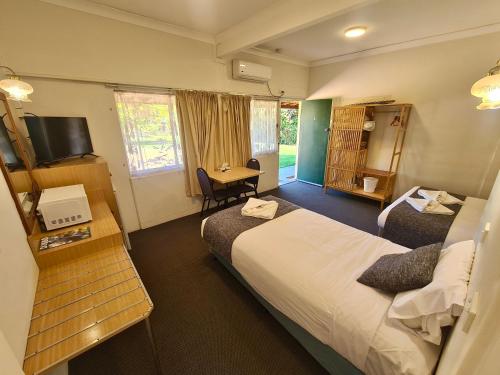 a hotel room with two beds and a desk at Bridge Motel Wellington in Wellington
