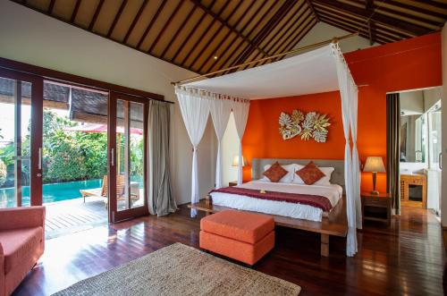a bedroom with a bed with an orange wall at Enchanting Canggu Villa in Tumbak Bayuh