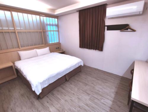 a small room with a bed and a window at AOIKE Hot Spring Hotel in Jiaoxi