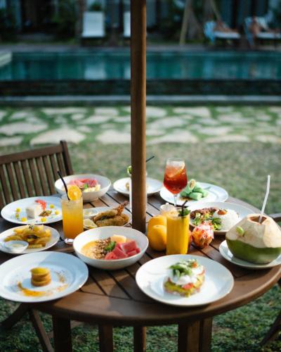 クタにあるTIKA Lombokの食べ物の皿が置かれた木製のテーブル