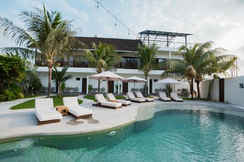 a resort with a swimming pool and chairs and a building at Suksma Guesthouse in Canggu