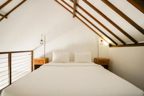 a bedroom with a large white bed in a room at Suksma Guesthouse in Canggu