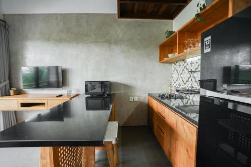 a kitchen with a black counter top and wooden cabinets at Suksma Guesthouse in Canggu