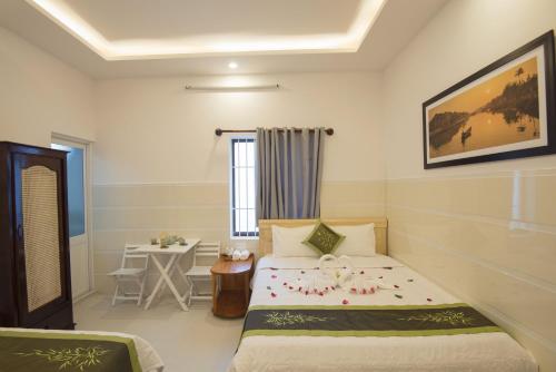 a bedroom with a bed and a table in it at Bong House Homestay 2 in Hoi An