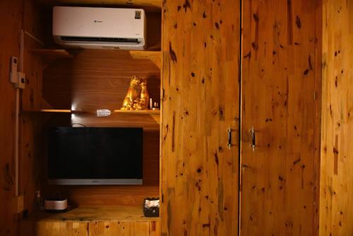 a room with a tv and a wooden wall at ROSIE HOMESTAY Hà Giang in Ha Giang