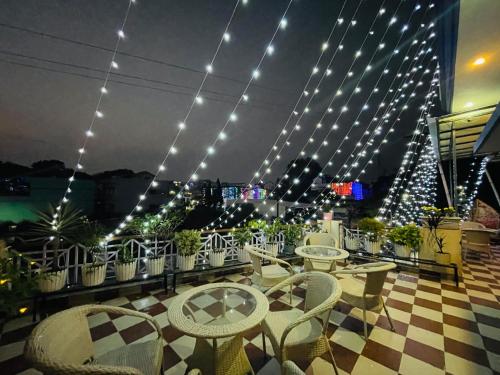 a rooftop patio with tables and chairs and lights at Stayble Homestay in Dehradun