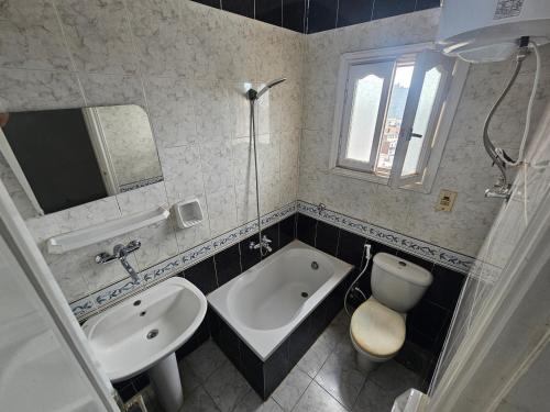 a bathroom with a tub and a sink and a toilet at Rasheed International Hotel - Families Only in Rashīd