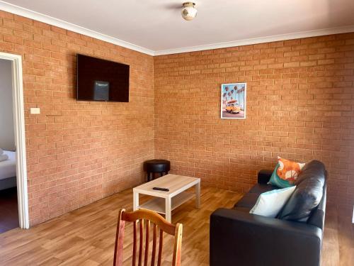 a living room with a couch and a brick wall at Waves Geraldton in Geraldton