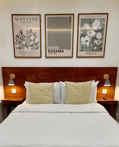 a bedroom with a bed with three pictures on the wall at Cozy Cottage in Kabankalan
