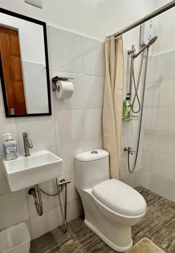 a bathroom with a toilet and a sink and a shower at Cozy Cottage in Kabankalan
