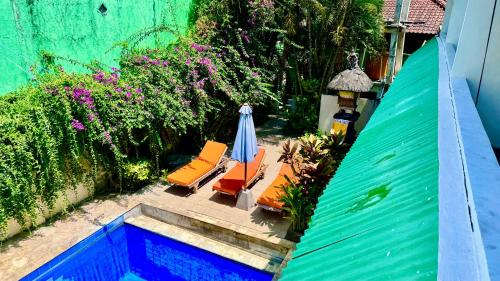 Elle offre une vue sur la terrasse dotée de chaises et d'un parasol. dans l'établissement Ellenbrook Rooms 18 by Mulia Cottage, à Seminyak