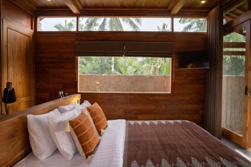 a bedroom with a bed with a large window at Kini Sebatu in Tampaksiring