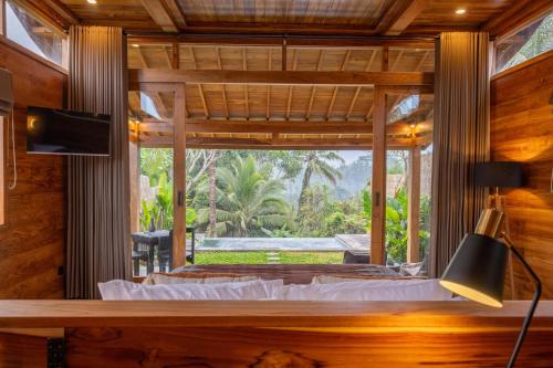 a bedroom with a bed and a large window at Kini Sebatu in Tampaksiring