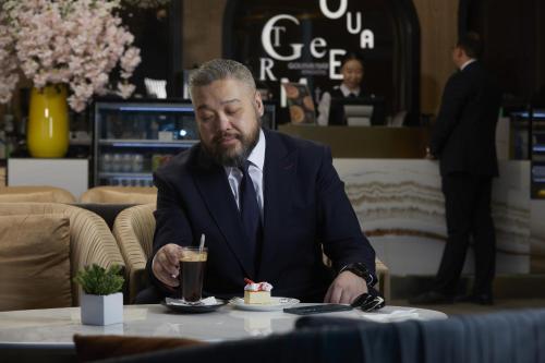 a man in a suit sitting at a table with a dessert at Novotel Ulaanbaatar in Ulaanbaatar