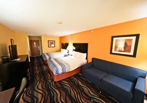 a hotel room with a bed and a couch at Rock Island Inn & Suites Streator , IL in Delbert Egan Housing Project