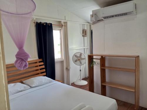 a bedroom with a bed and a window and a fan at Christina's Guest House OFFICIAL in Little Corn Island