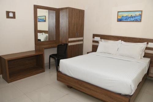 Un dormitorio con una cama, un espejo y una silla. en Vasantham Inn, en Tiruchchirāppalli