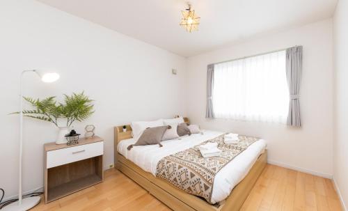 a white bedroom with a bed and a window at Sky Blu 旭川駅徒歩10分 モニター付きワークスペース完備 in Asahikawa