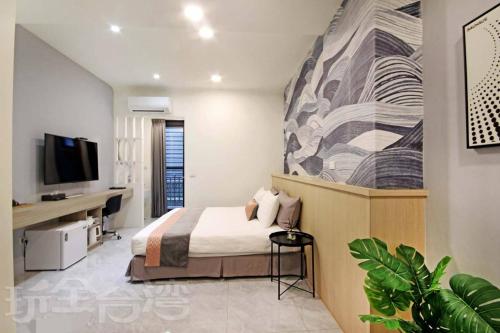 a bedroom with a bed and a desk and a tv at Station Sea B&B in Fangliao