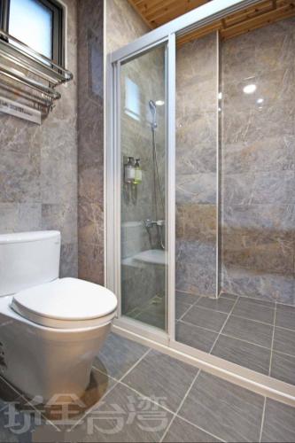 a bathroom with a toilet and a glass shower at Station Sea B&B in Fangliao