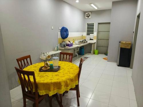 a kitchen with a table with a yellow table cloth at Anis Gerikhomestay, Taman Desa Baiduri 15 in Gerik