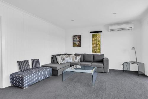 a living room with a couch and a table at Seascape Beach House in Pambula Beach