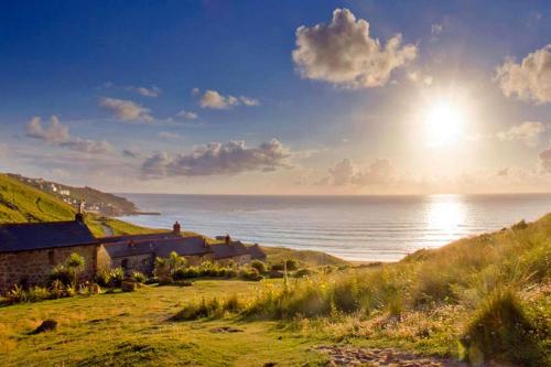 a house on a hill next to the ocean at White Rose Beach Cottage Sea-Views Garden in Sennen