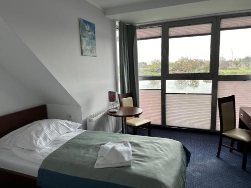 a bedroom with a bed and a table and windows at Marina Wolin in Wolin