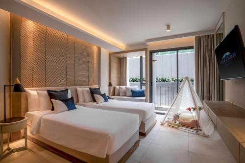 a hotel room with two beds and a couch at Howard Johnson by Wyndham Pattaya JC in Na Jomtien