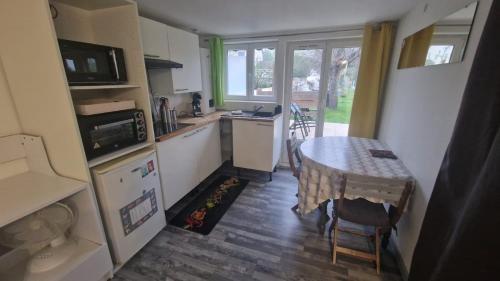 une petite cuisine avec une table et une salle à manger dans l'établissement Studio Marmotte, quartier marais, terrasse en rez de jardin, matelas confort, à Bourges