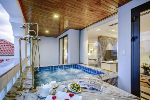 a soaking tub in a room with a kitchen at Gallery Hotel & Spa - Le Pavillon Hoi An Group in Hoi An