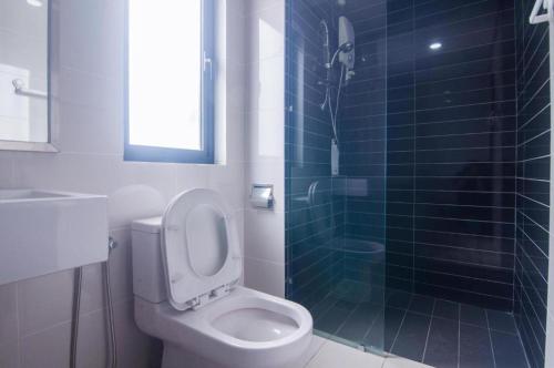 a bathroom with a toilet and a glass shower at Islamic Santai Santai Homestay - Centrus Soho Cyberjaya in Cyberjaya
