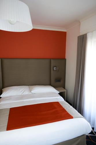 a bed in a room with a red wall at Hotel Eden in Geneva