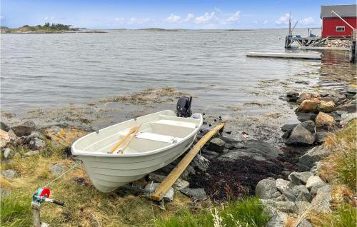 a boat sitting on the shore of a body of water at Lovely Home In Smøla With Kitchen in Smøla
