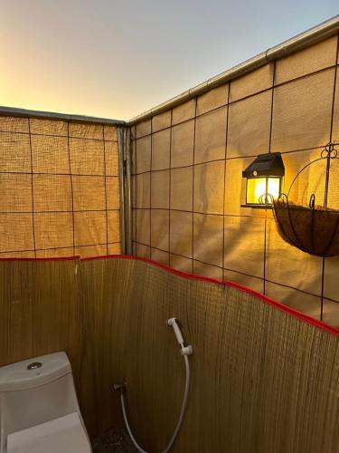 a bathroom with a toilet and a light on the wall at Golden dune Bedouin camp in Al Wāşil