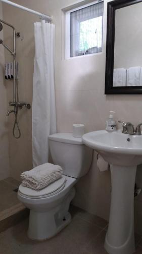 a white bathroom with a toilet and a sink at Ocean Villa Guam in Tamuning