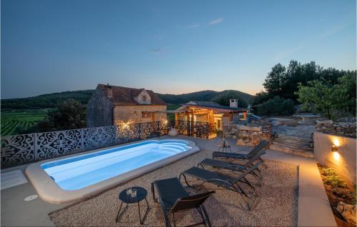a swimming pool on a patio with chairs and a house at 2 Bedroom Gorgeous Home In Smokvica in Smokvica
