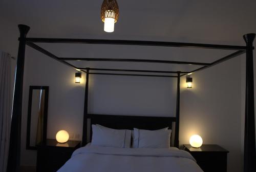 a bedroom with a bed with two lights on it at Wateera Jebel Sifah in As Sīfah