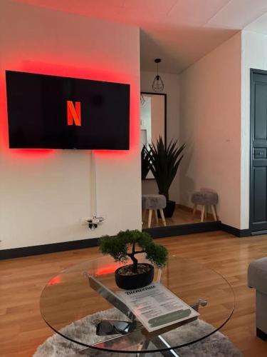 un salon avec une télévision sur un mur dans l'établissement Luxury Room - Havre de paix avec jacuzzi privé, à Bar-le-Duc