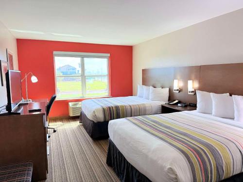 a hotel room with two beds and a window at Country Inn & Suites by Radisson, Harlingen, TX in Harlingen