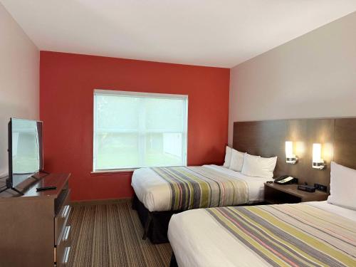 a hotel room with two beds and a window at Country Inn & Suites by Radisson, Harlingen, TX in Harlingen